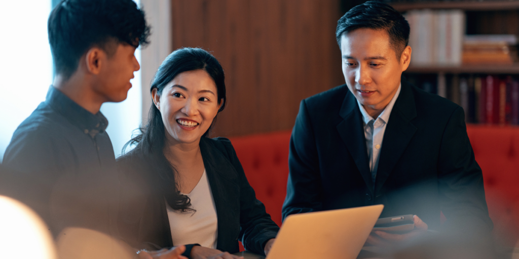 A leader in discussion with their team, laptop open, in a Singapore office