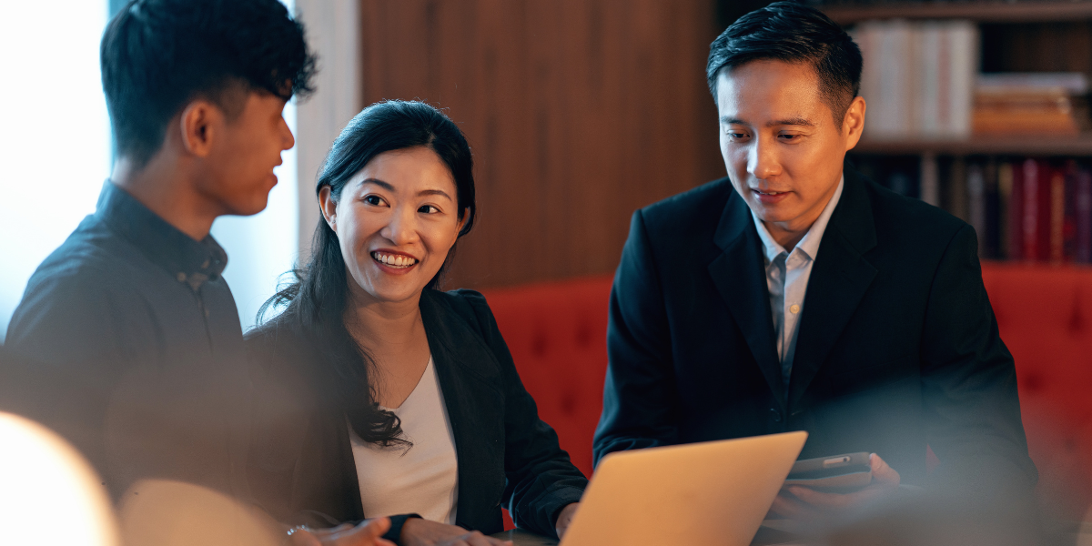 A leader in discussion with their team, laptop open, in a Singapore office
